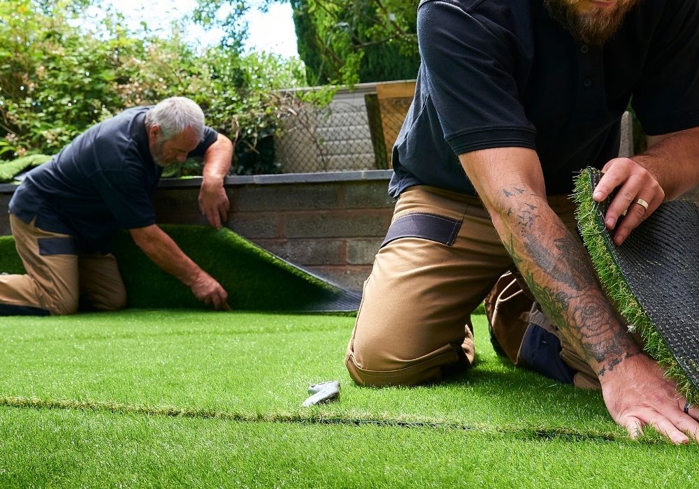 Installers fitting artificial grass lawn